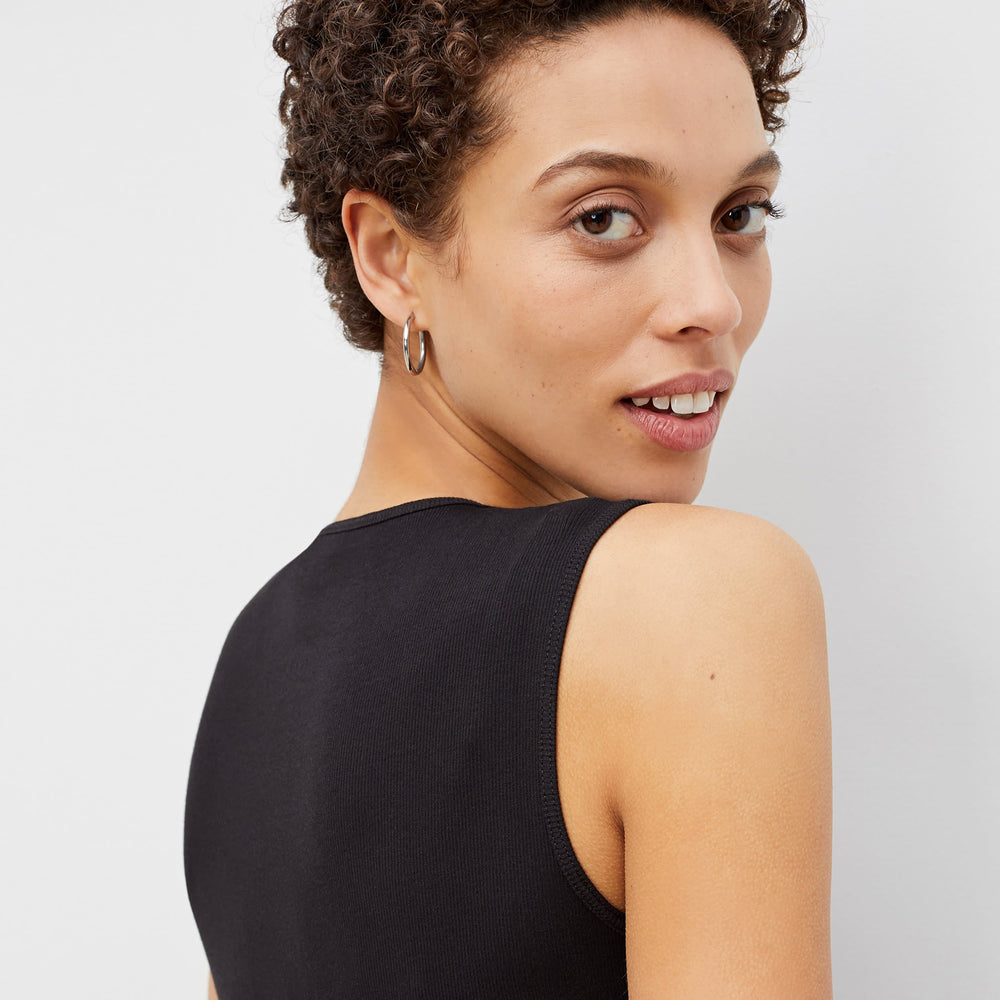 Back image of a woman standing wearing the paige top in fine ribbed cotton in black