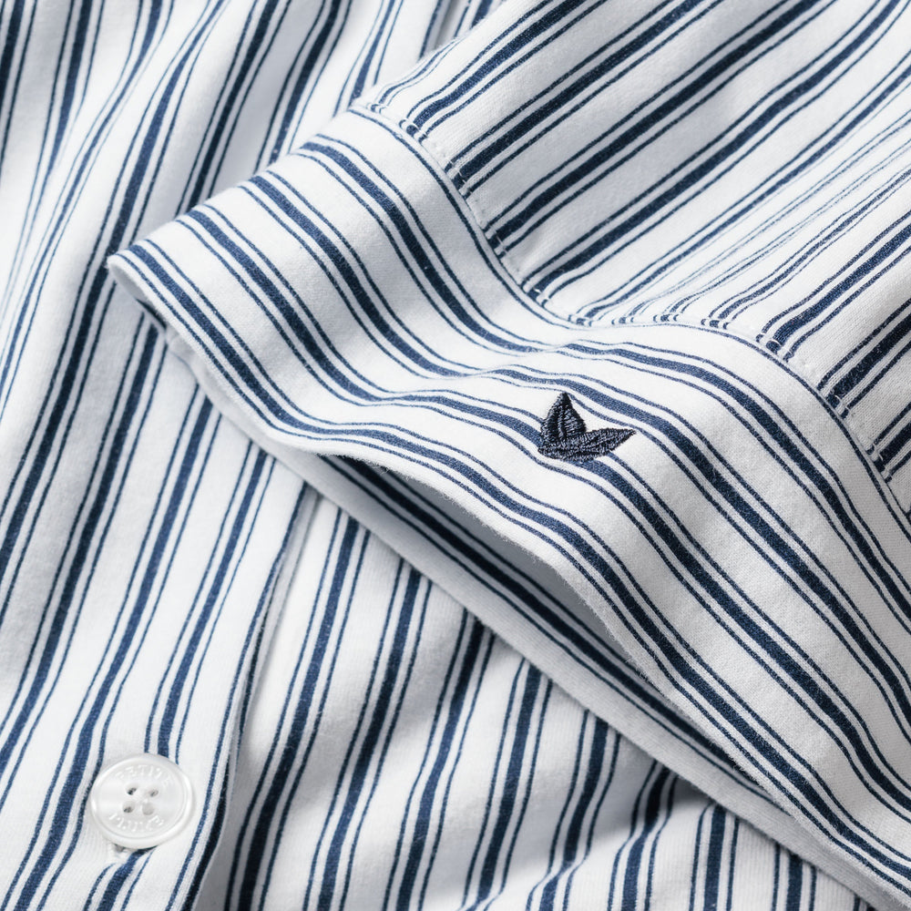Close-up of a blue and white striped shirt with a button and brand logo.