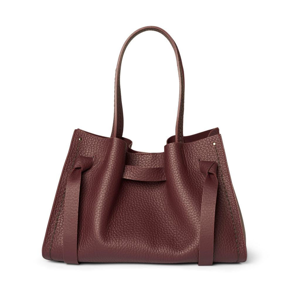 A pebbled leather handbag in a deep burgundy color, featuring dual top handles and a structured silhouette, shown against a plain white background.