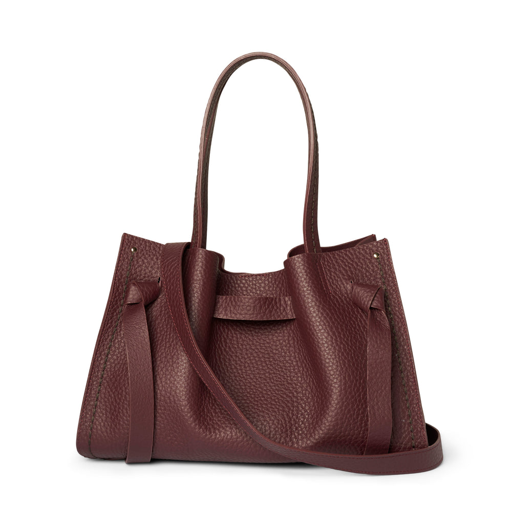 A dark burgundy pebbled leather handbag with double top handles and a detachable shoulder strap, shown against a plain white background.