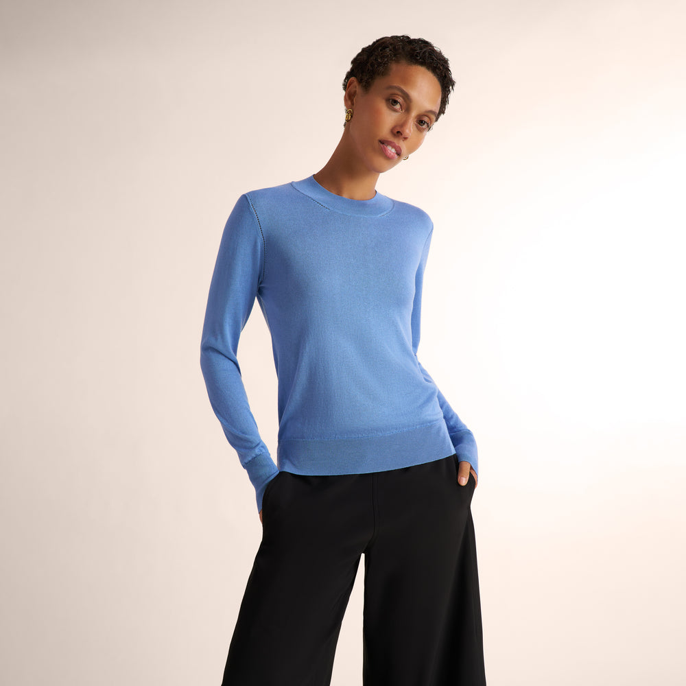 Woman wearing a blue splendor color long sleeve sweater with black wide leg pants