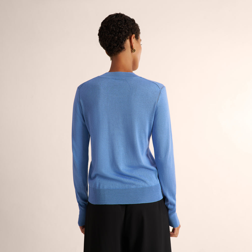 Woman wearing a blue splendor color long sleeve sweater with black wide leg pants and matching blazer