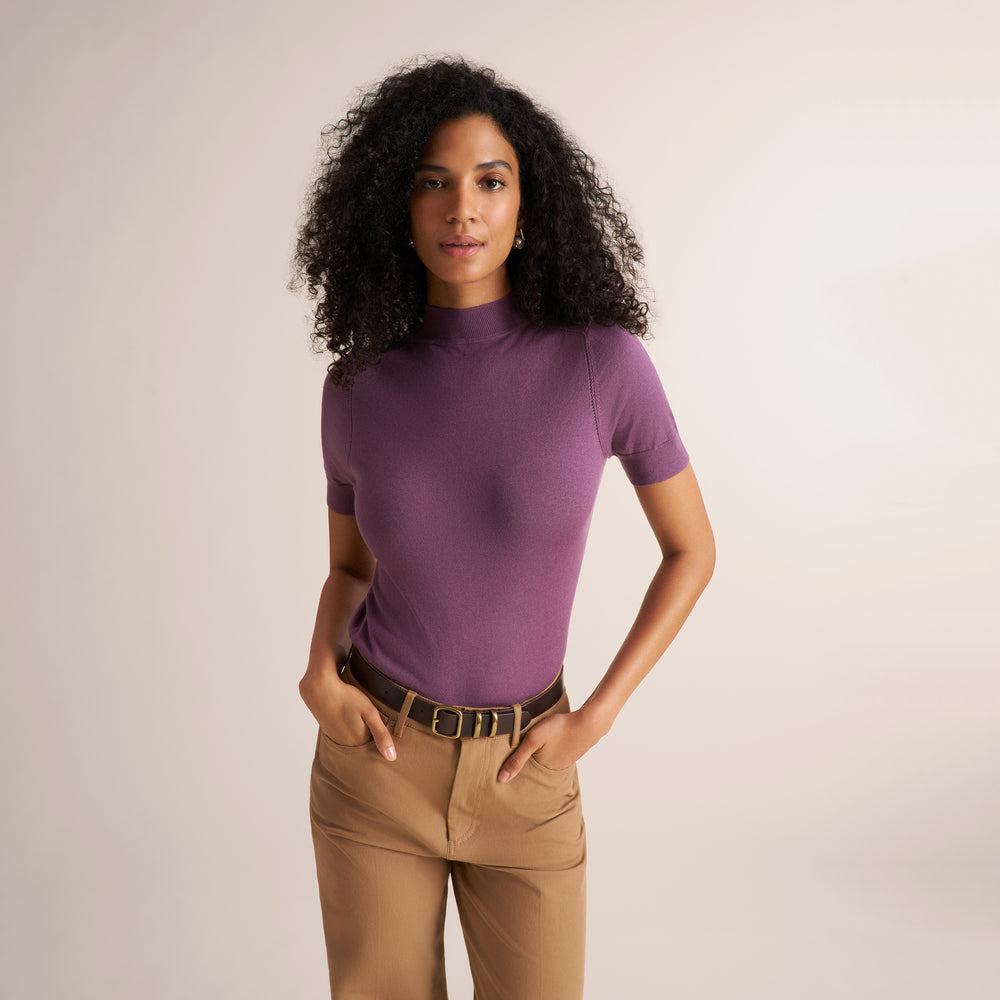 Woman wearing a purple fig color short sleeve sweater with beige wide leg pants
