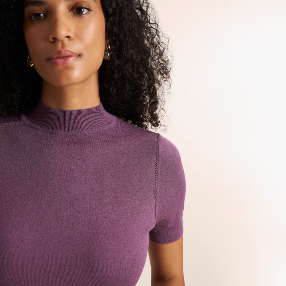 Woman wearing a purple fig color short sleeve sweater with beige wide leg pants