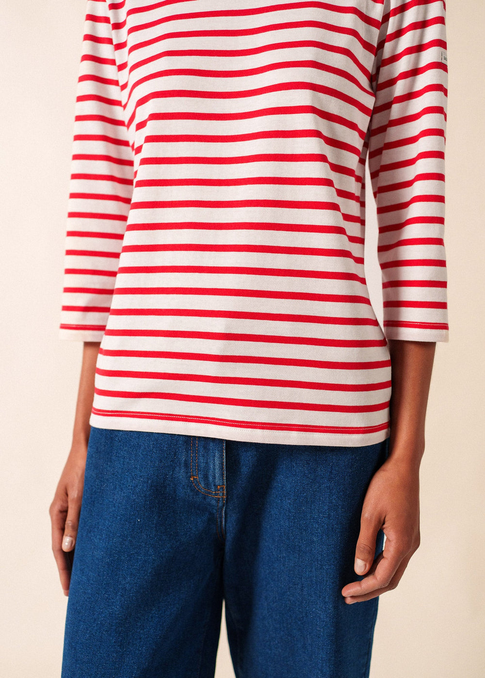 Red and white striped shirt worn by a person on a beige background