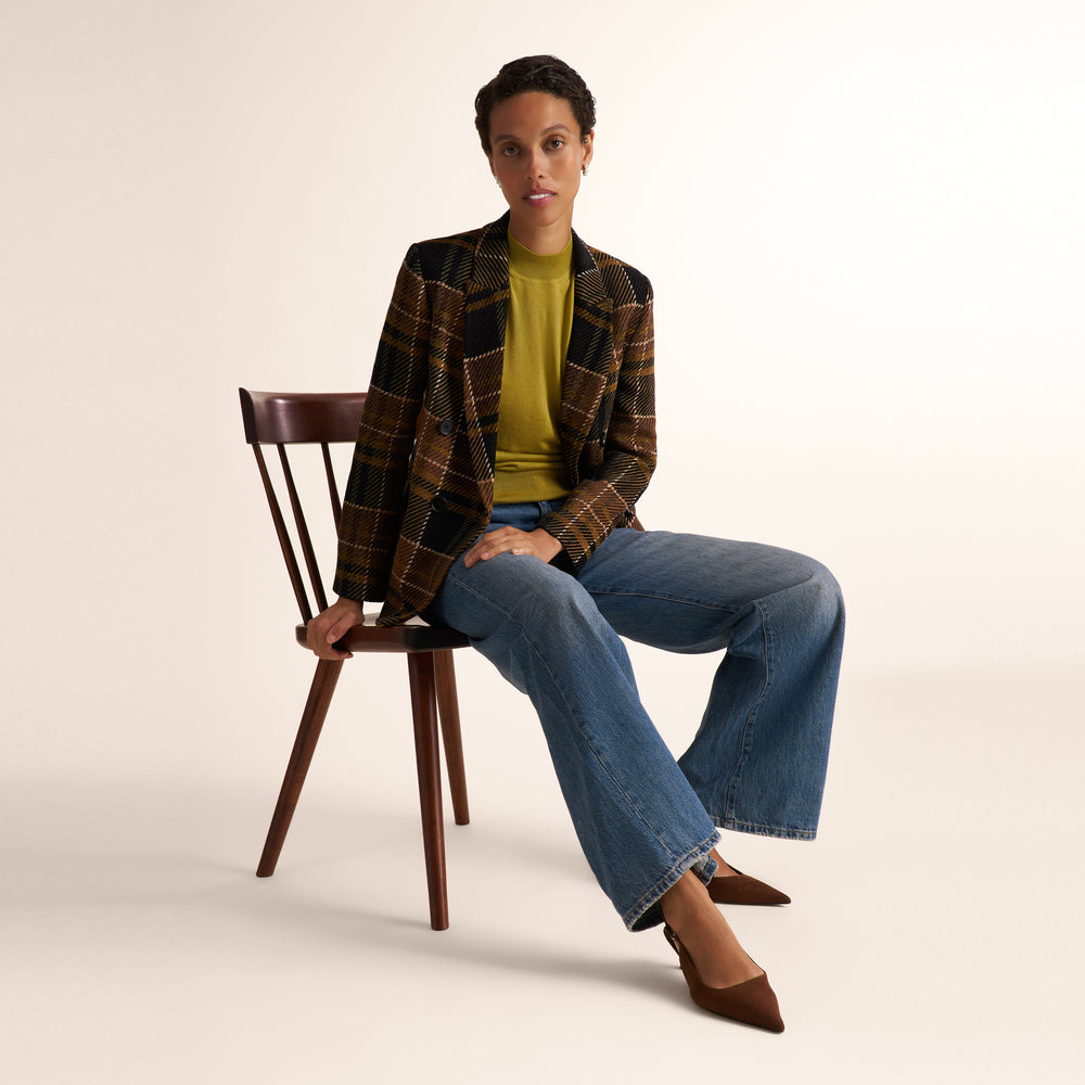 Woman wearing an olive green color short sleeve sweater with wide leg jeans and a plaid brown blazer