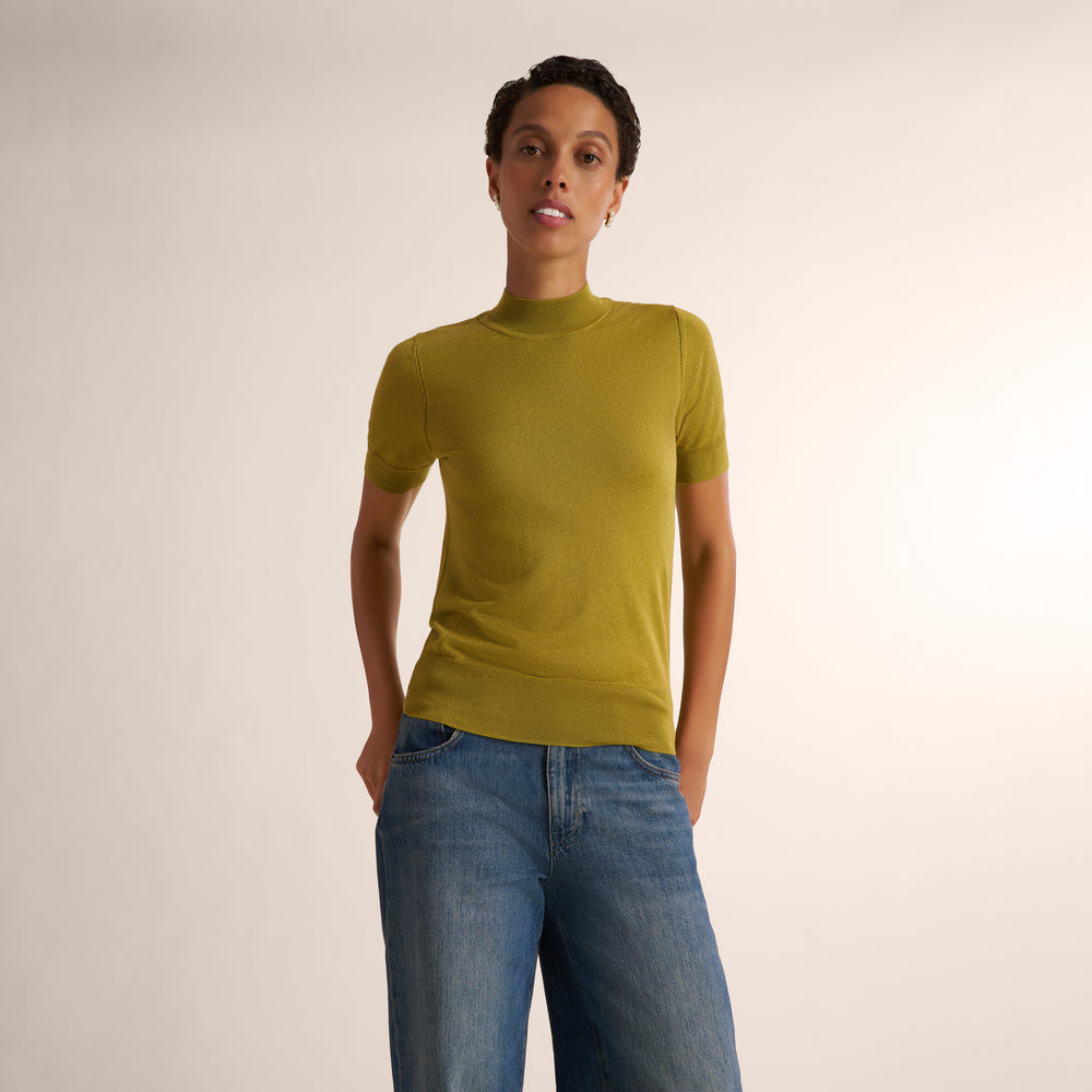 Woman wearing an olive green color short sleeve sweater with wide leg jeans