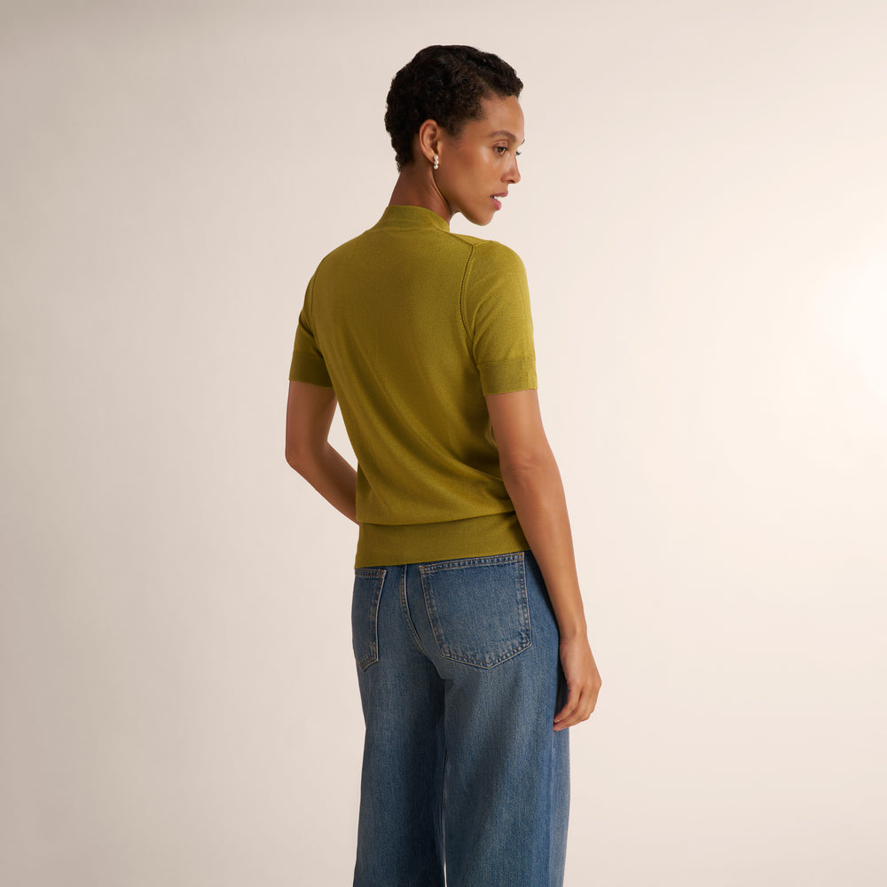 Woman wearing an olive green color short sleeve sweater with wide leg jeans