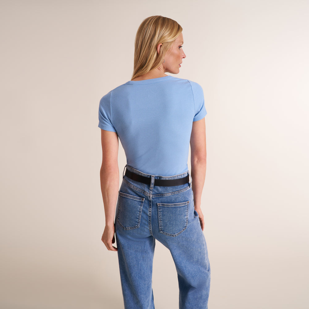 Woman wearing a light blue scoop neck short sleeve t-shirt with jeans and a belt