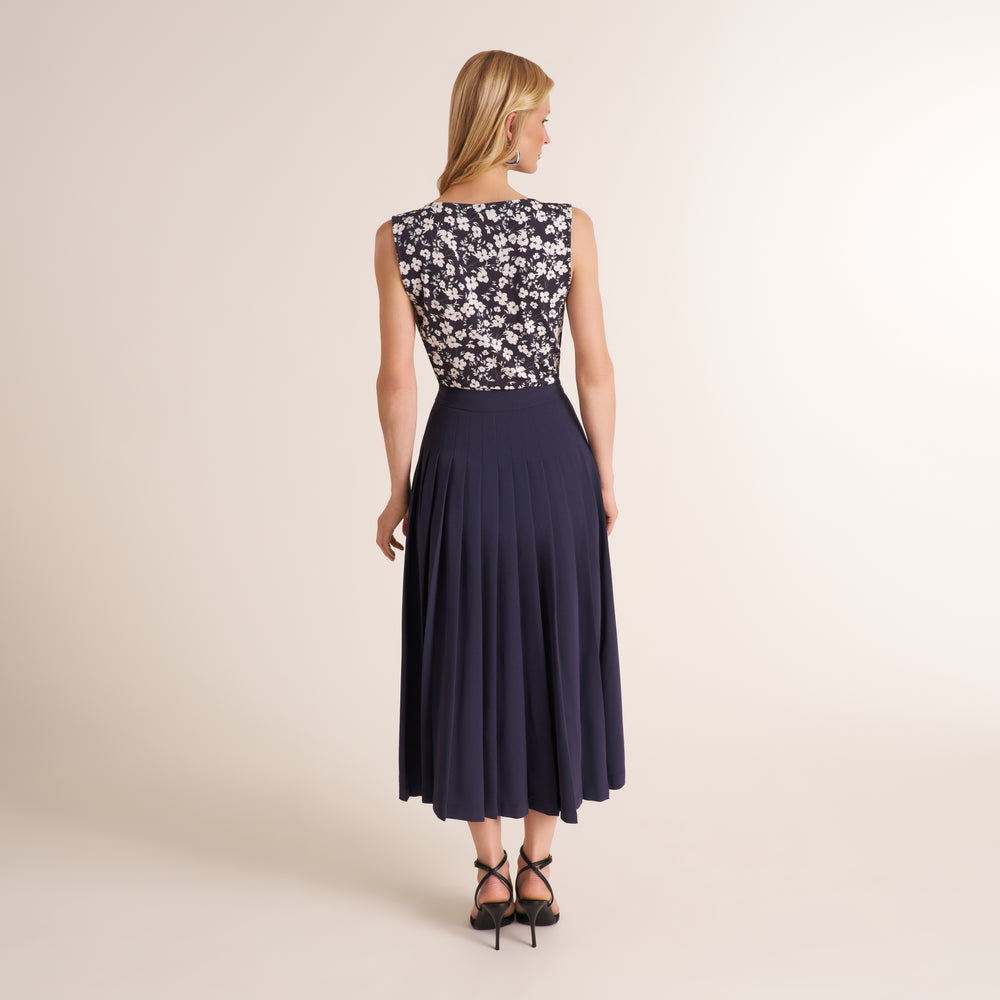 Woman wearing a a printed black and white top with a navy gray long skirt