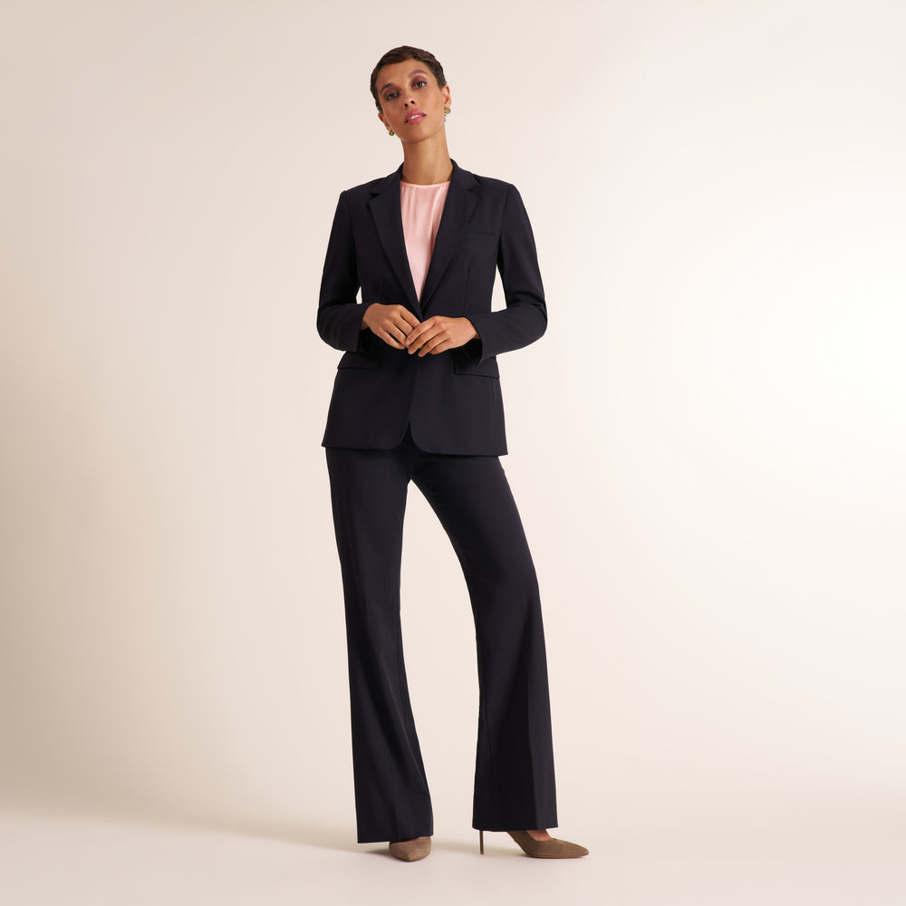 Woman wearing a flowy crew neck cap sleeve light pink silk charmeuse top with wide leg navy pants and matching blazer
