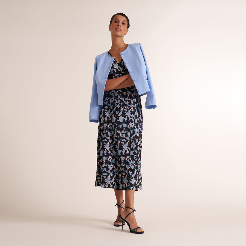 Woman wearing a navy and light blue printed top with a matching long skirt and light blue blazer over her shoulders