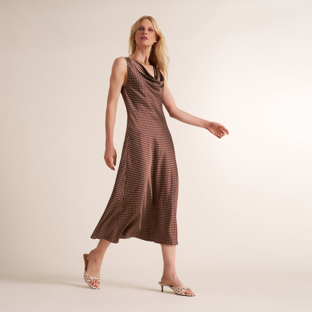 Woman wearing a sleevless maxi dress in a brown and white dot print