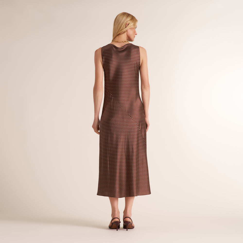 Woman wearing a sleevless maxi dress in a brown and white dot print