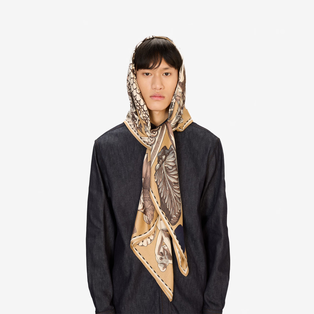 Person wearing a patterned scarf on a plain background