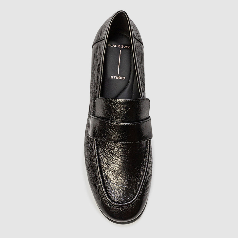 Black leather loafer shoe on a light gray background