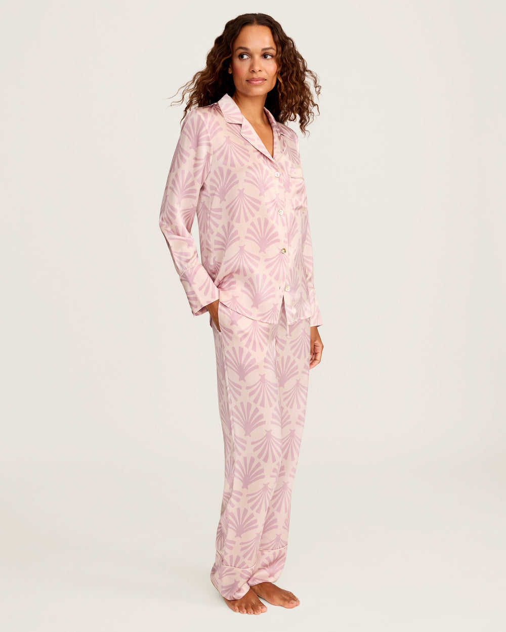 Woman wearing pink pajamas with a leaf pattern on a white background