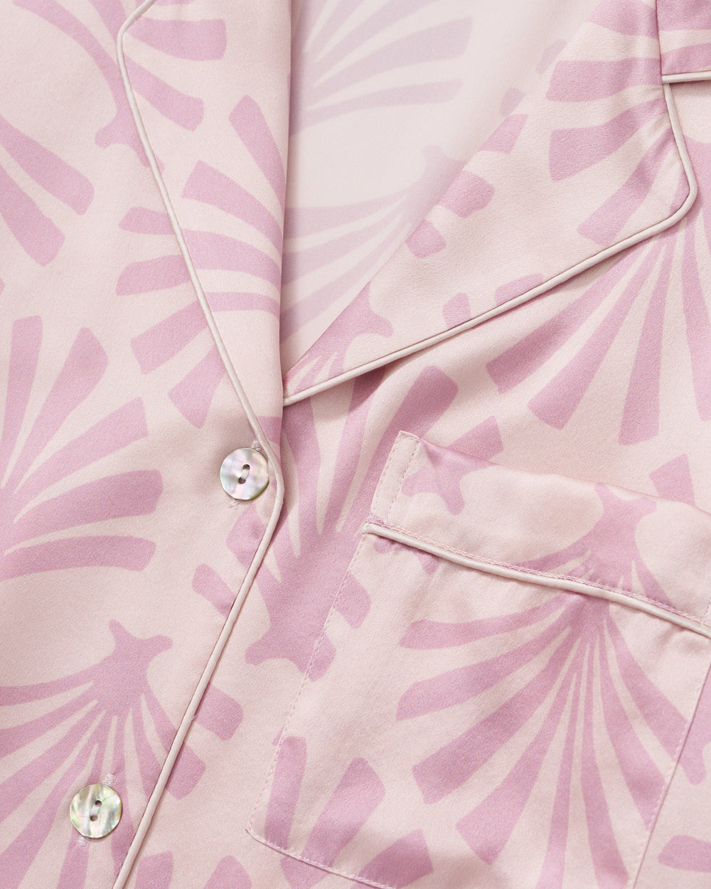 Close-up of a pink satin fabric with a subtle pattern and buttons.