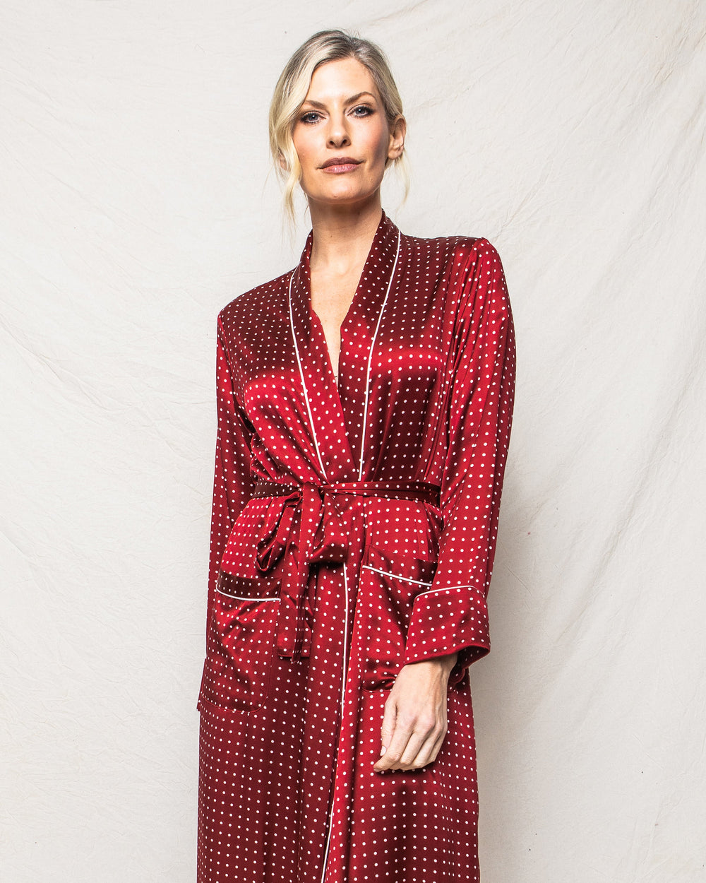 Woman wearing a red polka dot robe against a white background