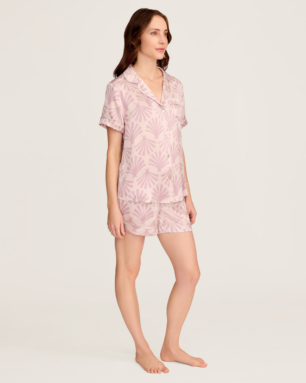 Woman wearing a pink pajama set with a leaf pattern on a white background