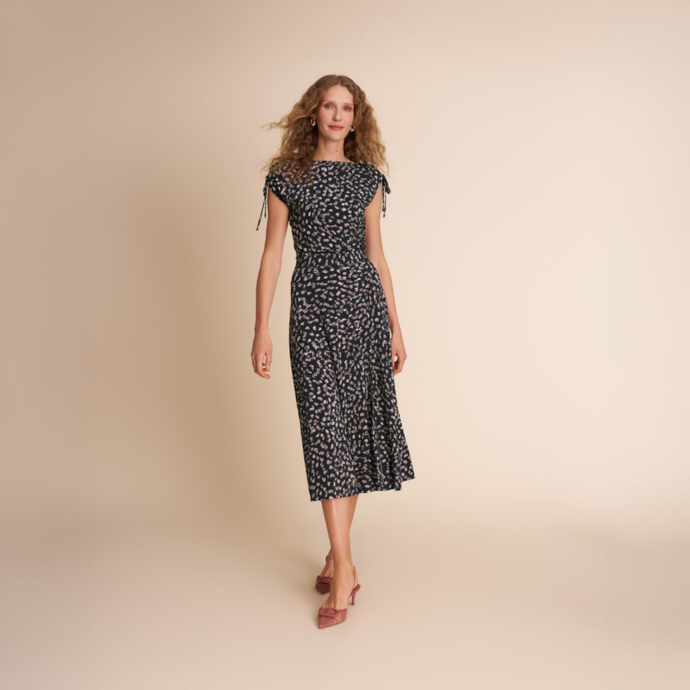 Woman wearing a black floral dress on a beige background
