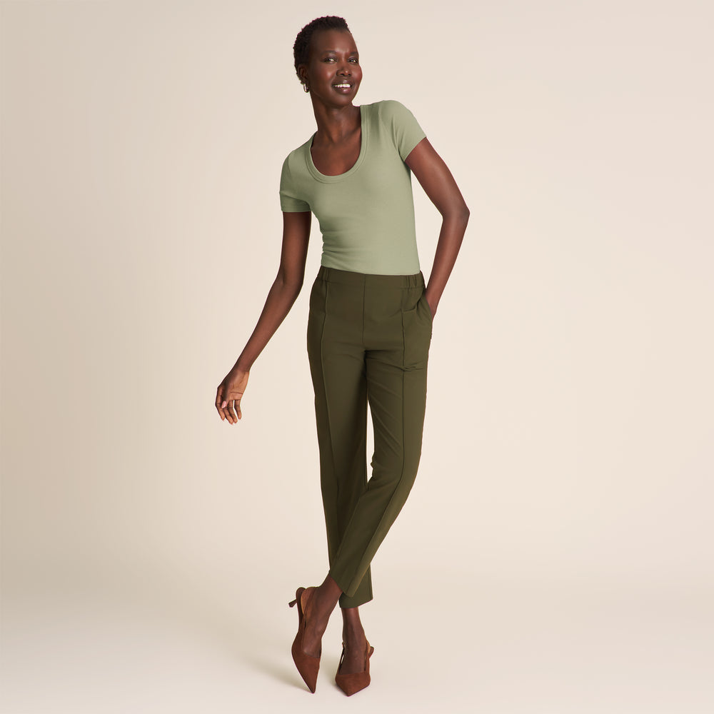 Woman wearing a green top and olive pants on a beige background