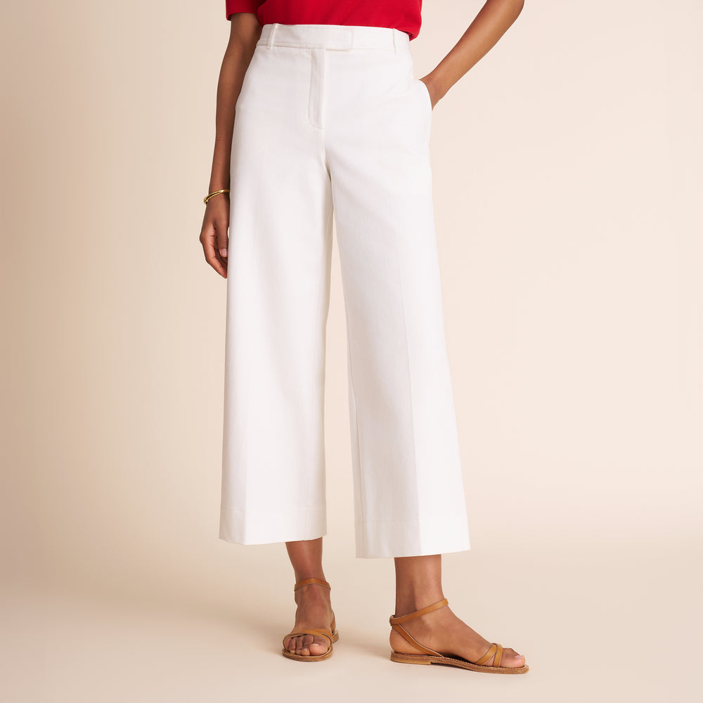 Person wearing white wide-leg pants with a red top on a beige background