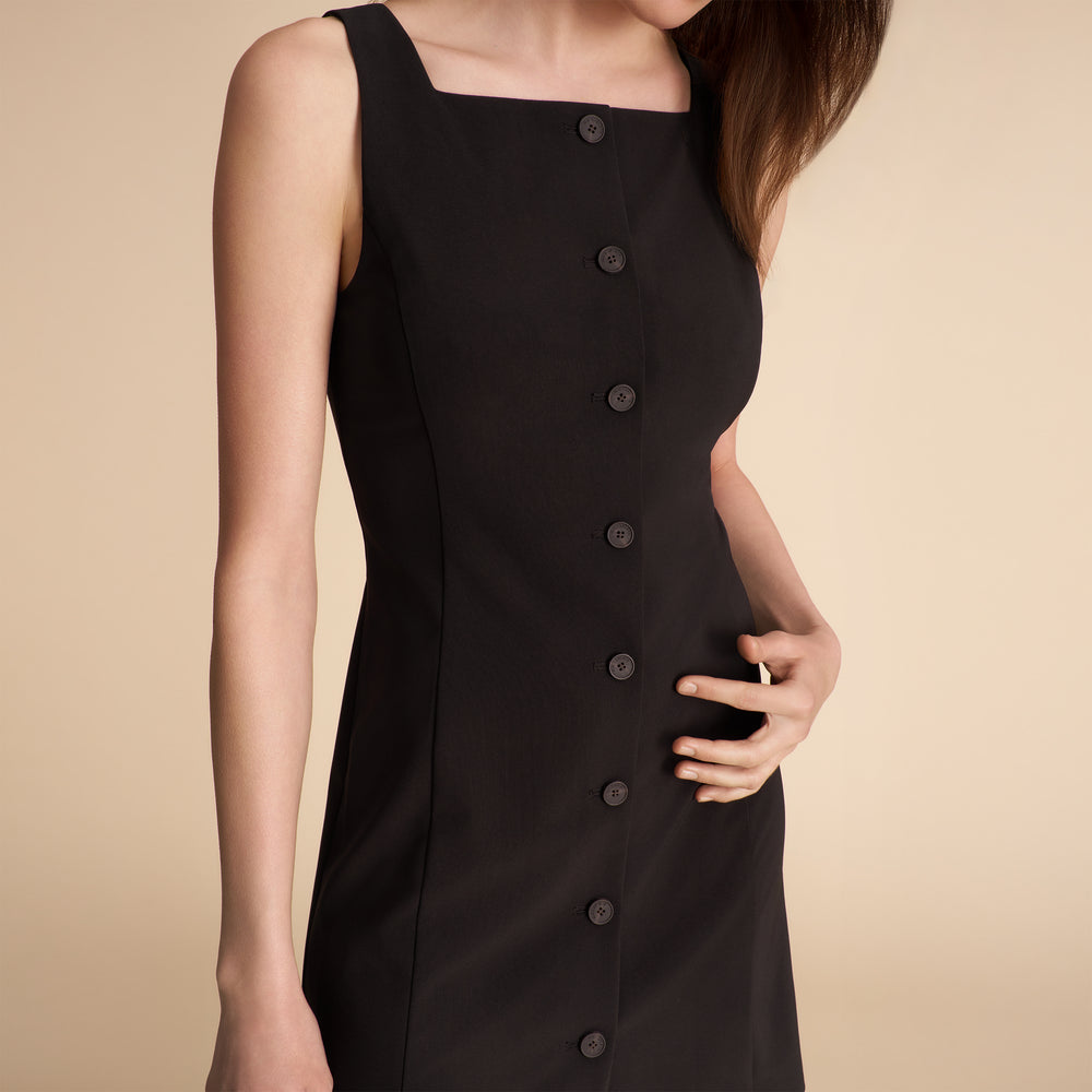 Black sleeveless dress with buttons on a beige background