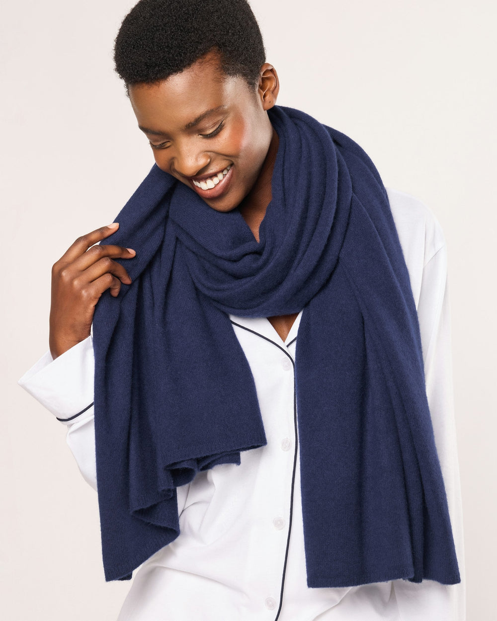 Woman wearing a navy blue scarf on a light background