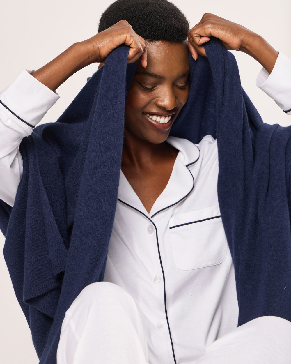 Person wearing white pajamas with navy blue scarf against a plain background