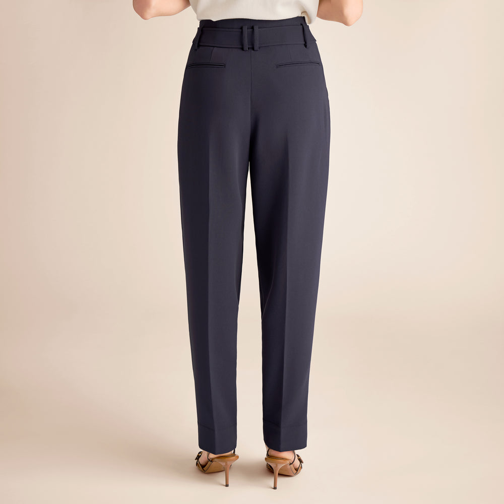 Navy blue pants worn by a person on a beige background