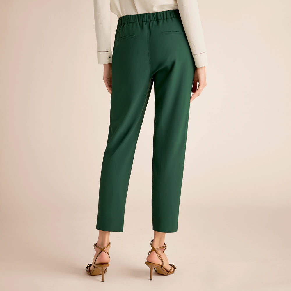 Green pants worn by a person on a beige background