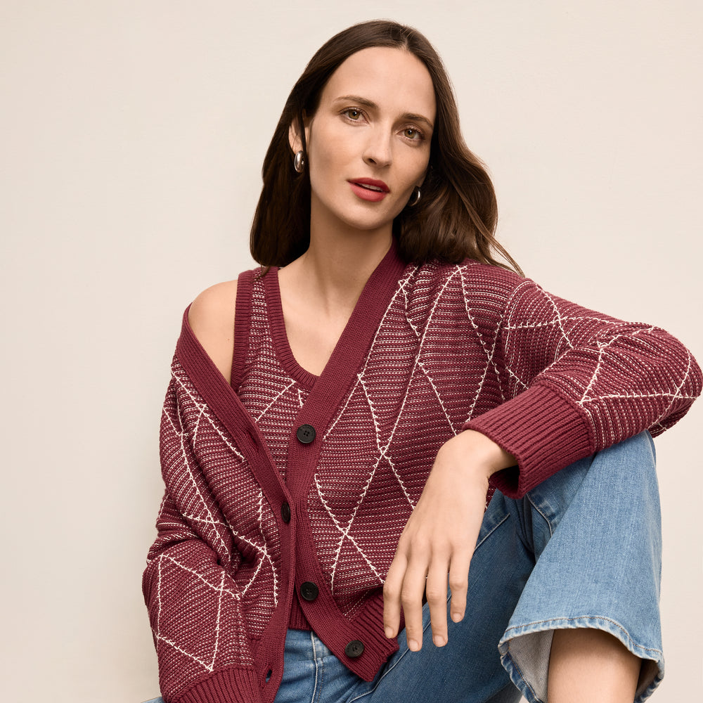 Woman wearing a patterned maroon cardigan against a beige background