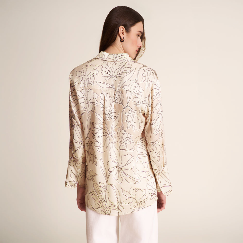 Woman wearing a beige floral blouse against a plain background
