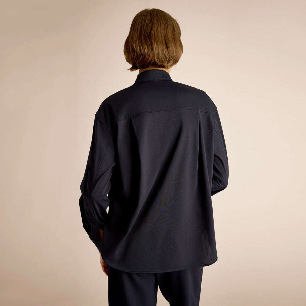 Person wearing a black shirt and pants against a beige background