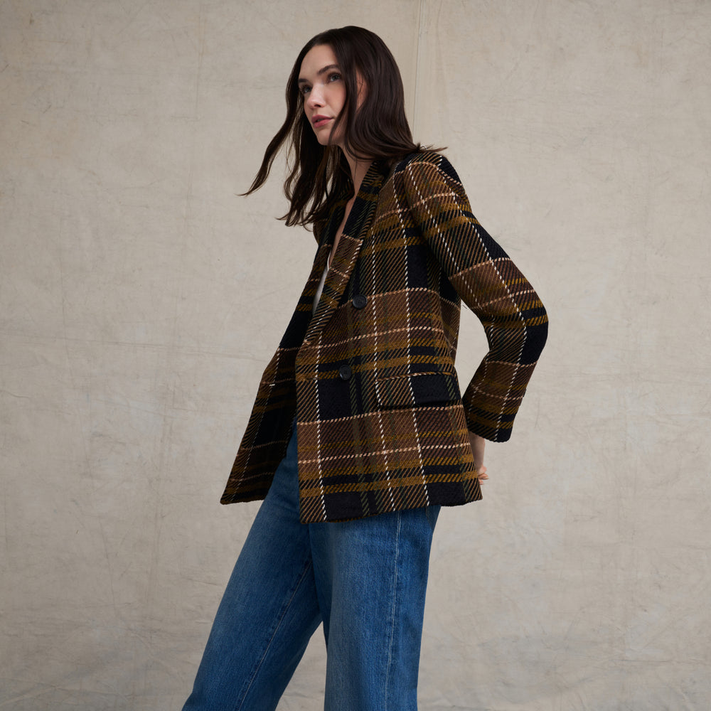 Woman wearing the O'Hara Blazer in Heritage Plaid with wide leg jeans on a beige background with blue floor