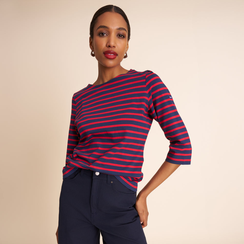 Woman wearing a red and blue striped shirt with navy pants on a beige background