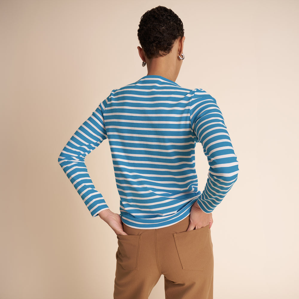 Person wearing a blue and white striped long-sleeve shirt on a beige background