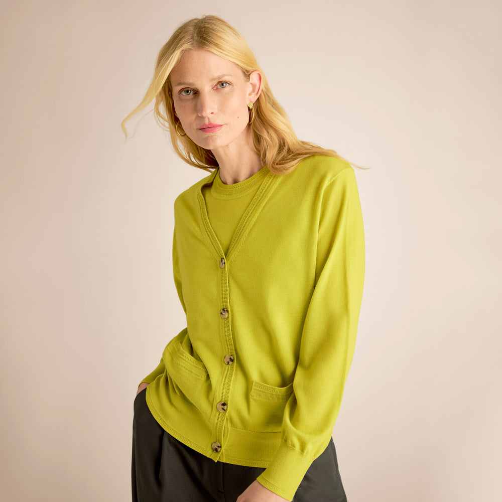 Woman wearing a green cardigan against a beige background