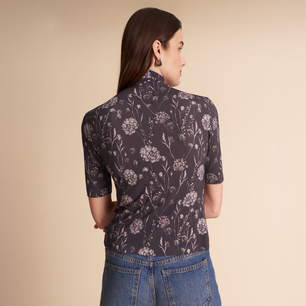 Woman wearing a patterned top and jeans on a beige background