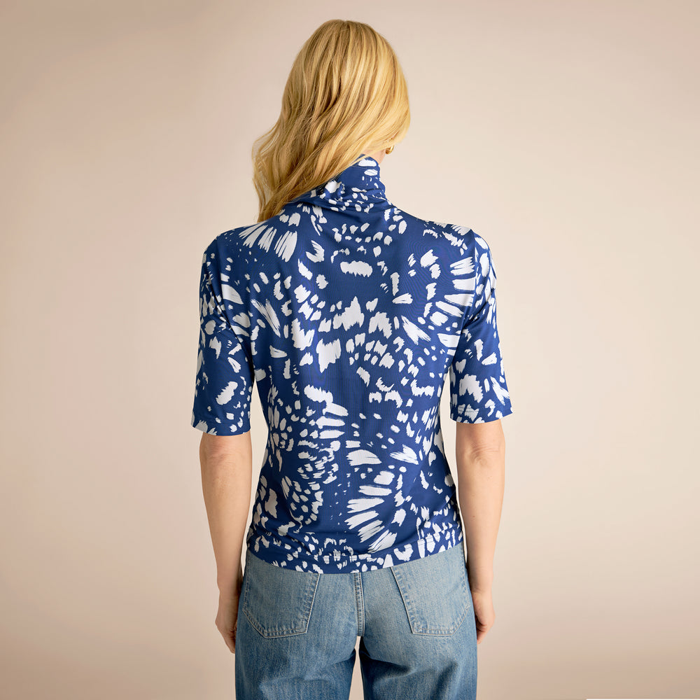Person wearing a blue and white patterned shirt with a beige background
