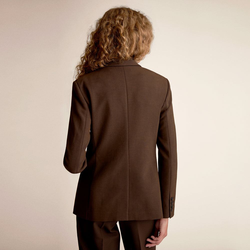 Person wearing a brown suit jacket on a beige background