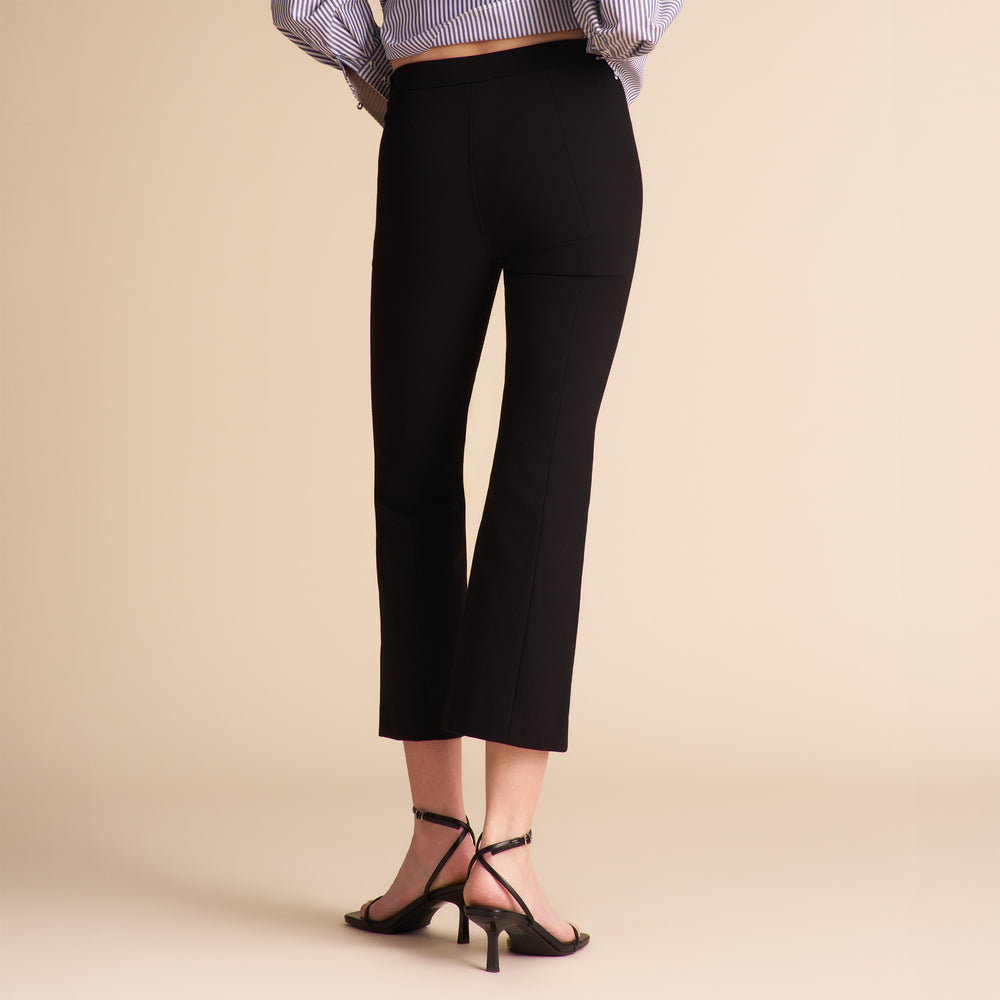Person wearing black pants on a beige background