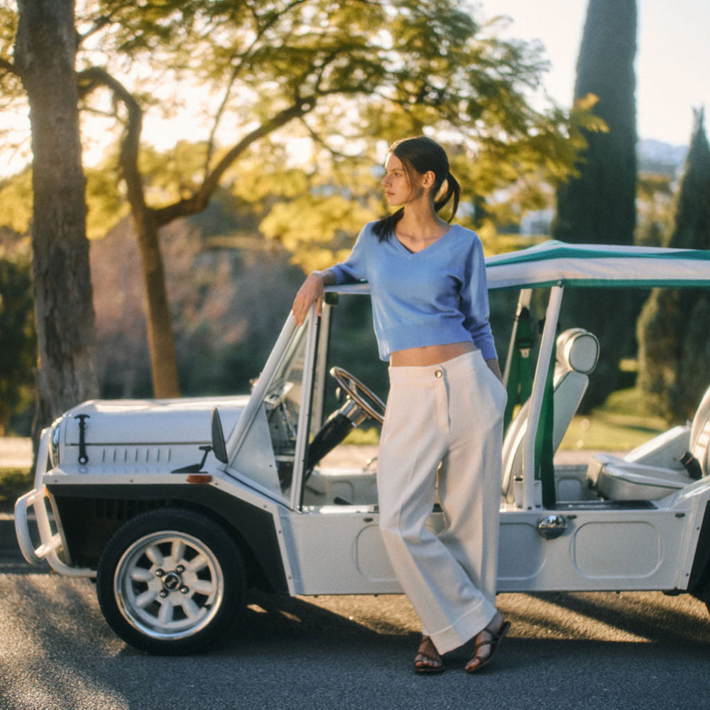 Woman standing next to a vintage car in a scenic outdoor setting