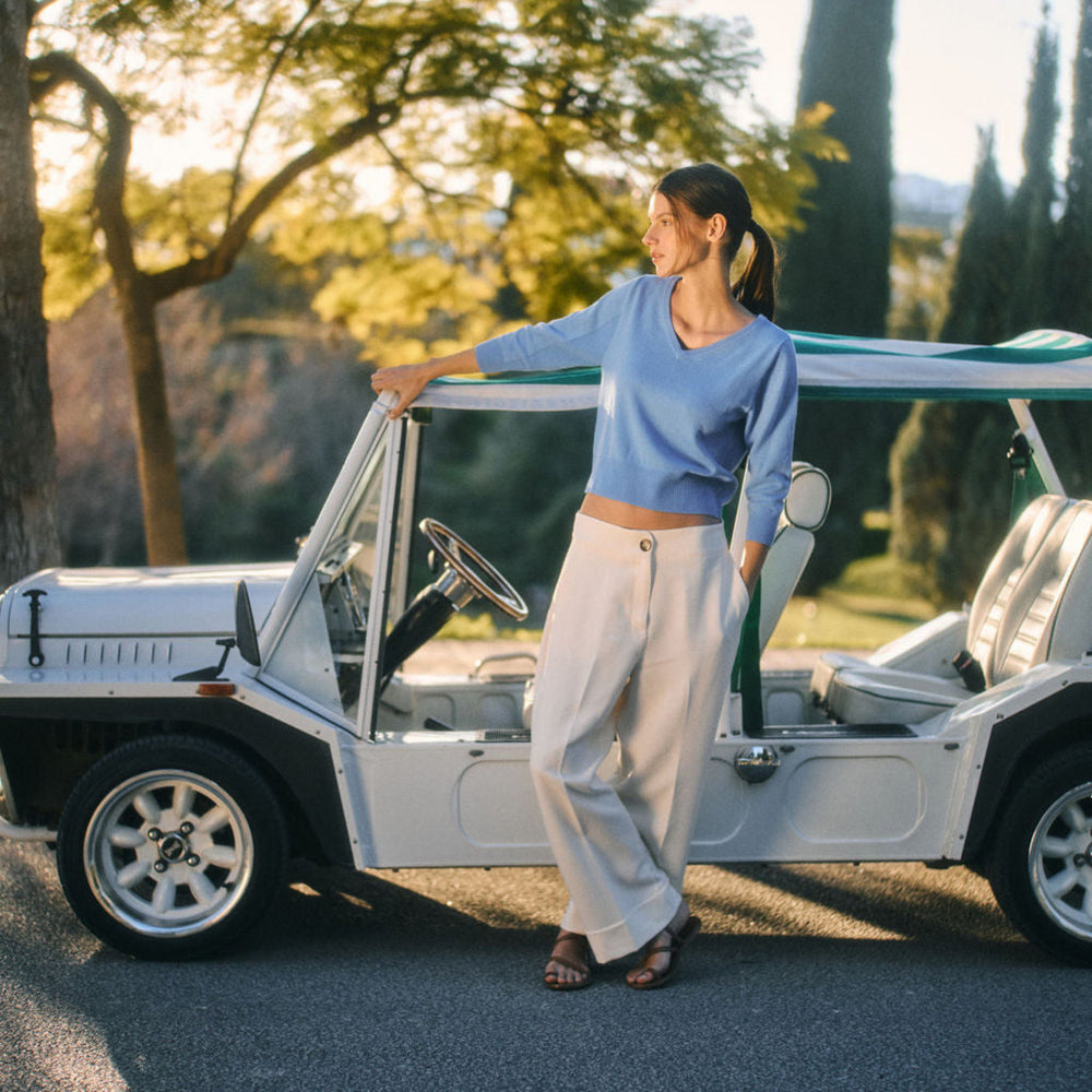 Woman standing next to a vintage car in a scenic outdoor setting
