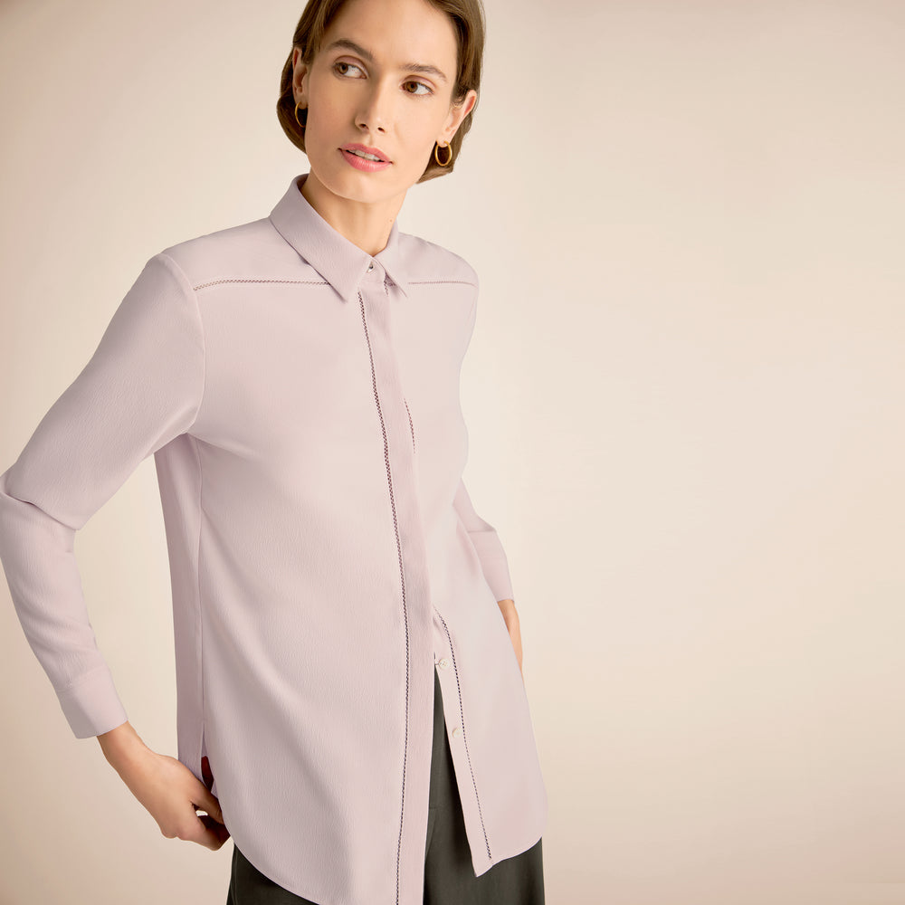 Woman wearing a light purple shirt against a beige background