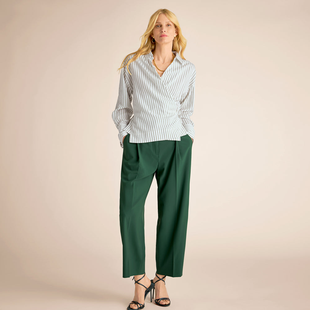 Woman wearing a striped shirt and green pants on a beige background