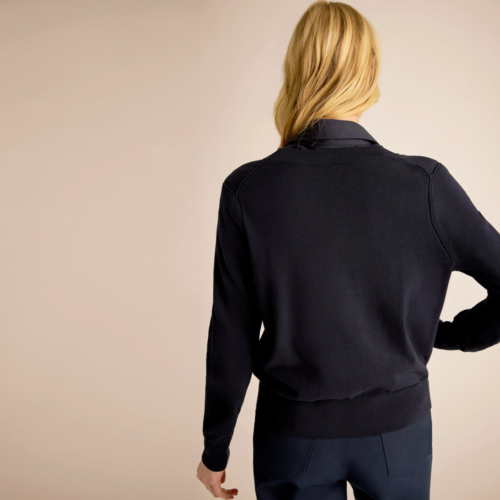Person wearing a dark blue jacket on a beige background