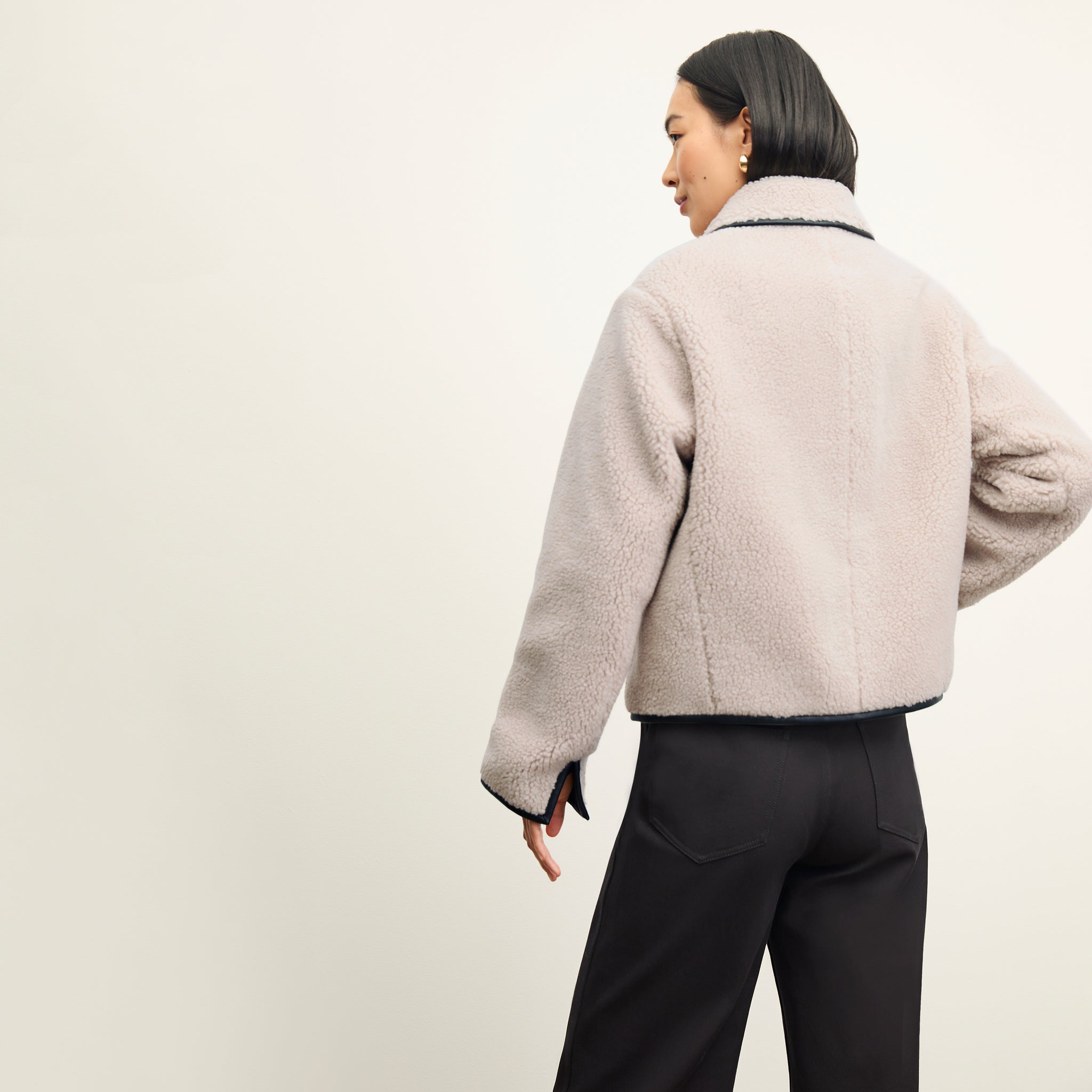 back image of a woman wearing the eli jacket in travertine