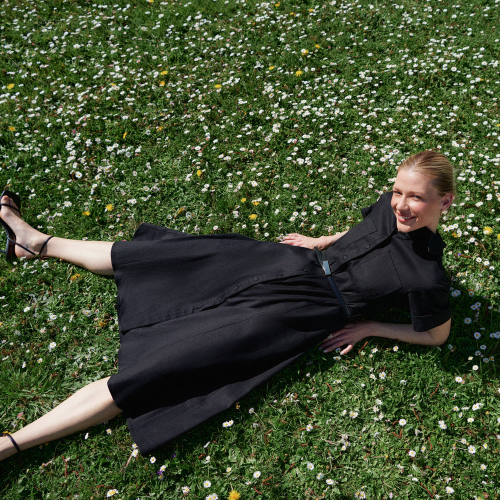 Woman in a black dress lying on grass with flowers